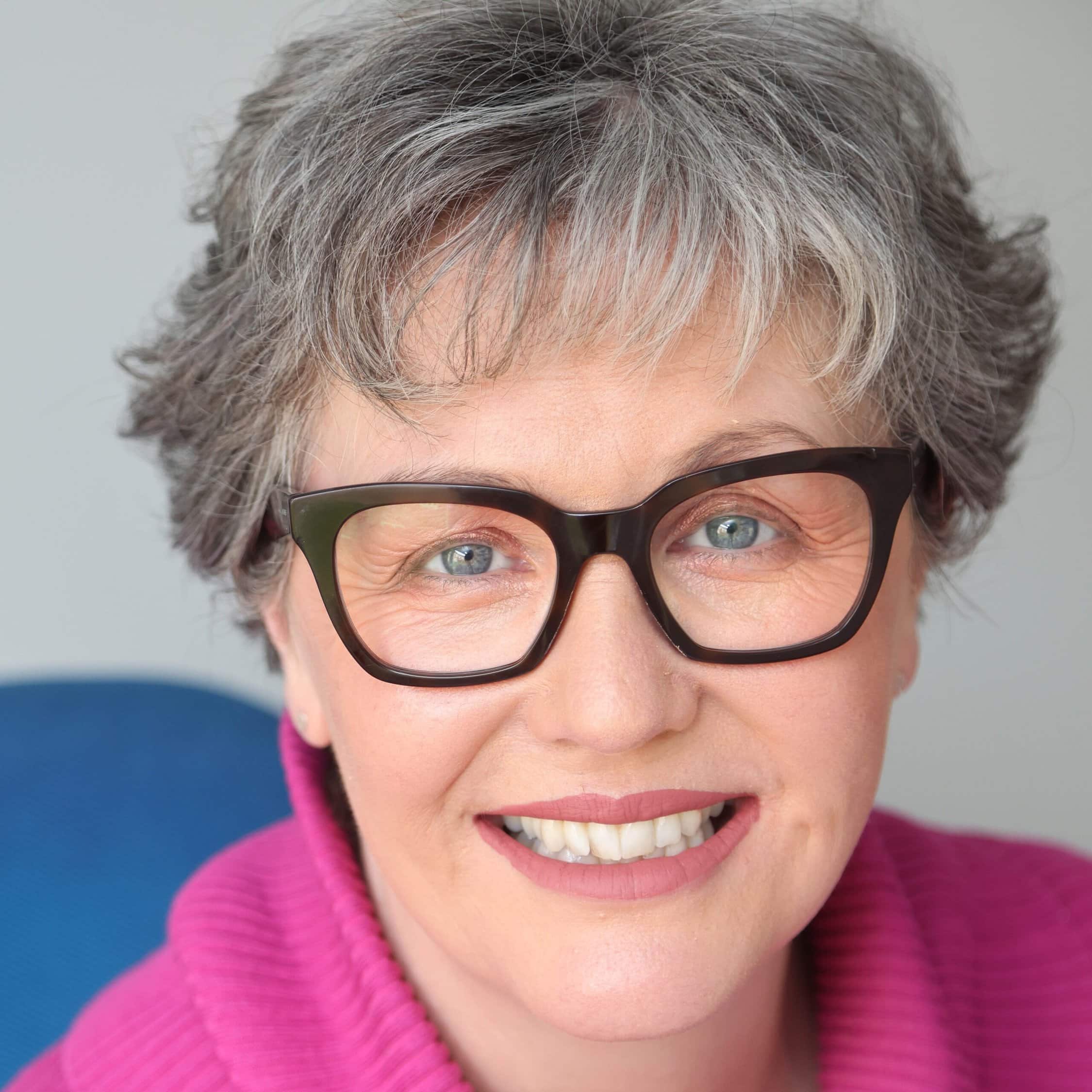 Smiling woman wearing glasses and pink jumper