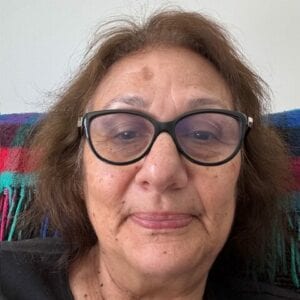 Person with glasses, neutral expression, colourful background