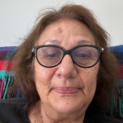 Person with glasses, neutral expression, colourful background